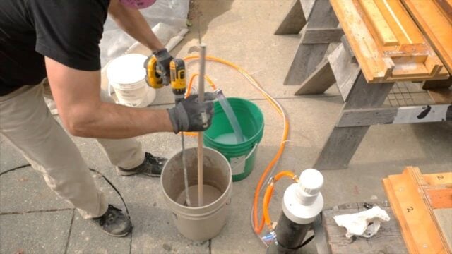 using a dowel to scrap mix off the side of the pail